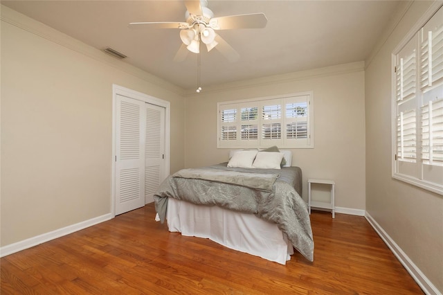 bedroom featuring a closet, visible vents, baseboards, and wood finished floors