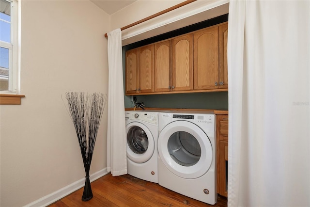 clothes washing area featuring dark wood-type flooring, washer and dryer, cabinet space, and baseboards