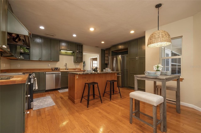 kitchen featuring a center island, light wood finished floors, open shelves, butcher block counters, and appliances with stainless steel finishes