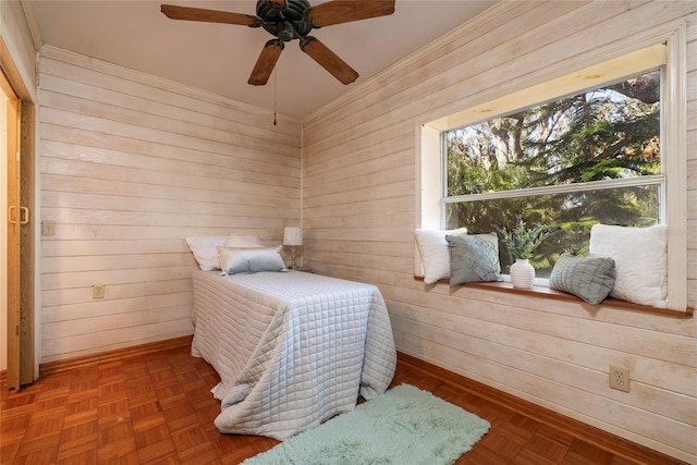 bedroom featuring ceiling fan, ornamental molding, and wooden walls