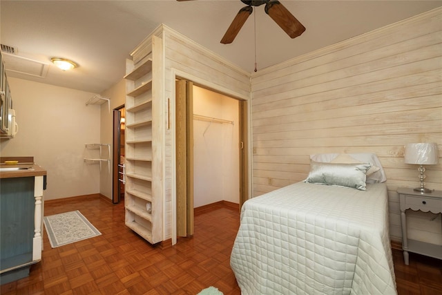 bedroom featuring baseboards, ceiling fan, attic access, and wooden walls