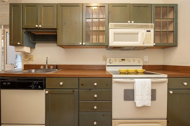 kitchen featuring glass insert cabinets, white appliances, and a sink