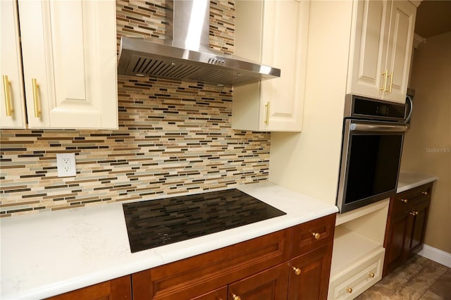 kitchen featuring backsplash, black electric cooktop, stainless steel oven, and wall chimney range hood