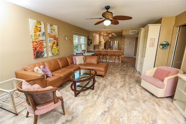 living room featuring a textured ceiling and ceiling fan