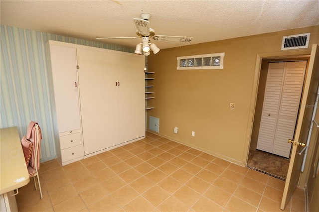 interior space featuring ceiling fan, light tile patterned floors, and a textured ceiling