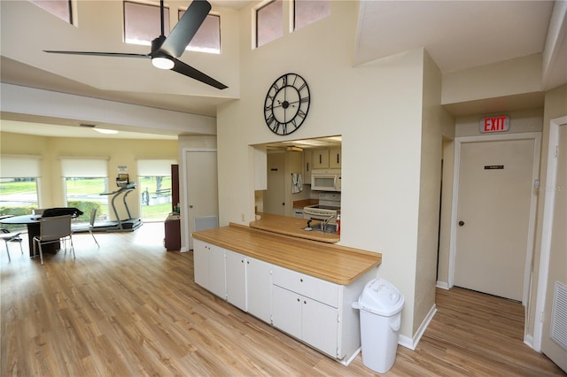 kitchen with white cabinets, light wood-type flooring, white appliances, and ceiling fan