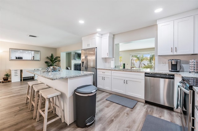 kitchen featuring white cabinets, a kitchen breakfast bar, sink, decorative backsplash, and stainless steel appliances