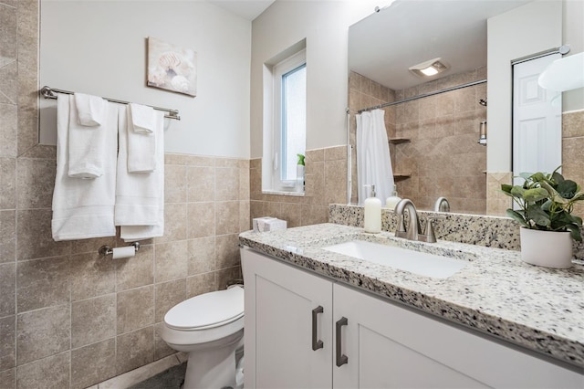 bathroom featuring curtained shower, vanity, tile walls, and toilet