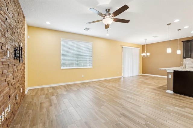 unfurnished living room featuring light hardwood / wood-style flooring, ceiling fan with notable chandelier, and sink