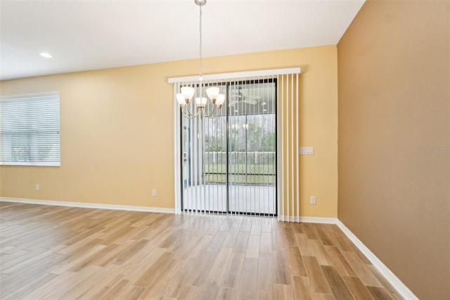 unfurnished dining area with light wood-type flooring and a notable chandelier