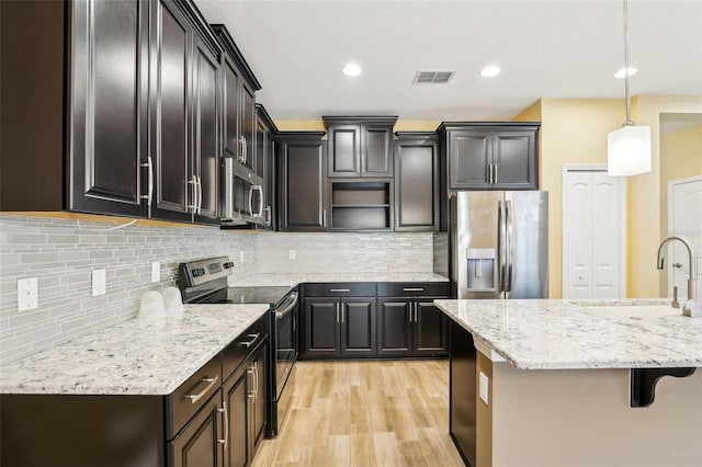 kitchen featuring sink, tasteful backsplash, pendant lighting, a kitchen bar, and appliances with stainless steel finishes