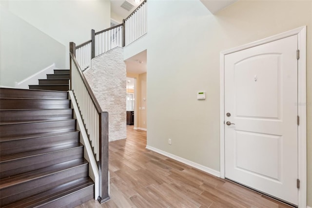 foyer entrance with a towering ceiling and light hardwood / wood-style floors