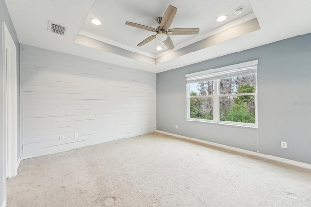 spare room with a tray ceiling, ceiling fan, light colored carpet, and ornamental molding