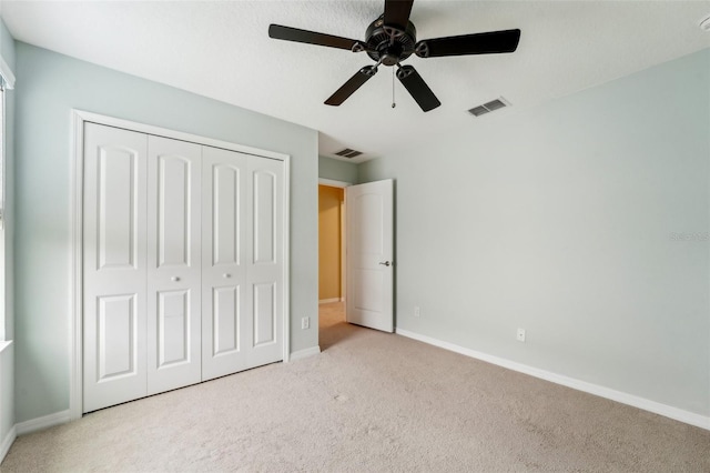 unfurnished bedroom featuring ceiling fan, a closet, and light colored carpet