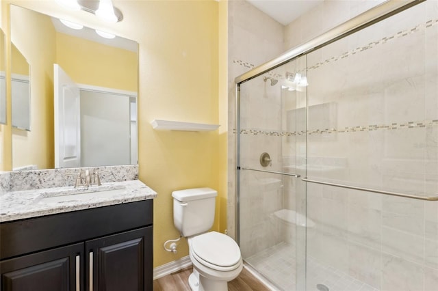 bathroom with vanity, hardwood / wood-style flooring, toilet, and a shower with shower door