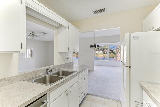 kitchen featuring light carpet, ceiling fan with notable chandelier, sink, white refrigerator, and white cabinetry