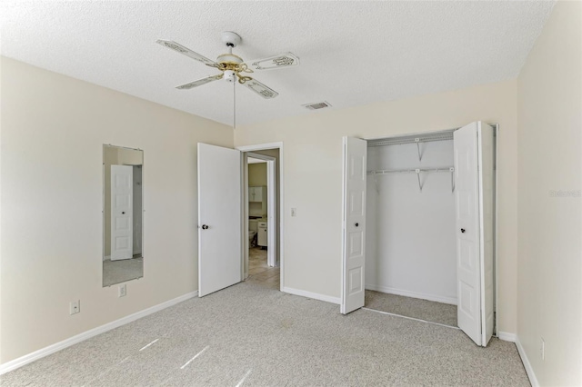 unfurnished bedroom featuring ceiling fan, a closet, light carpet, and a textured ceiling