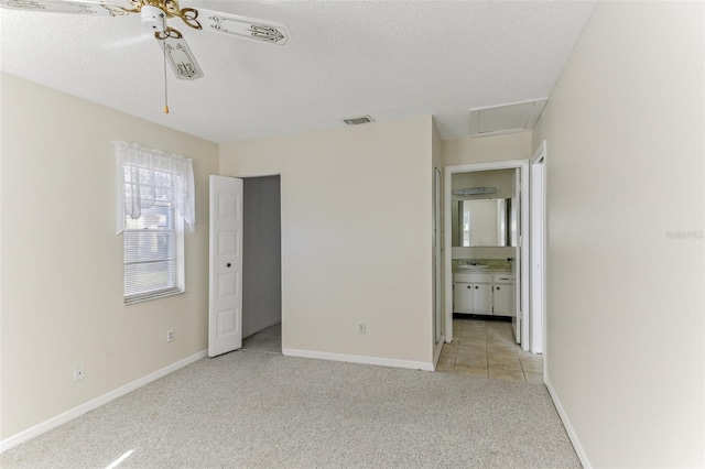 unfurnished bedroom featuring light carpet, ceiling fan, ensuite bathroom, and a textured ceiling