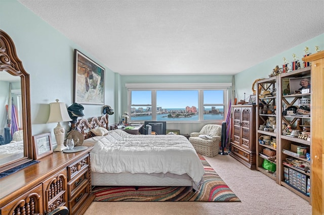 bedroom featuring a textured ceiling, carpet floors, and a water view