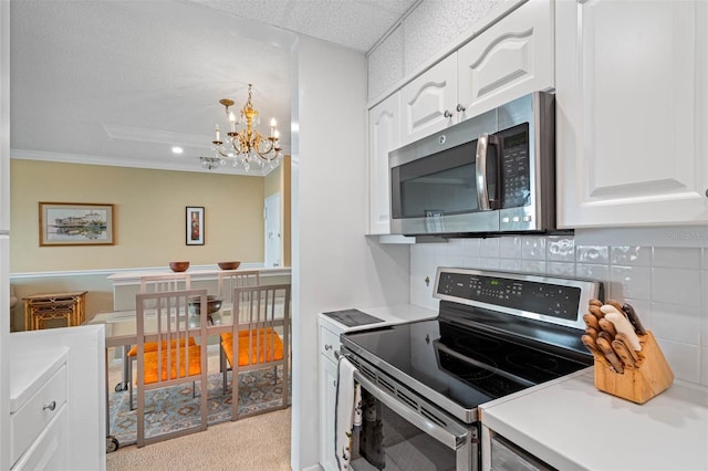 kitchen featuring tasteful backsplash, white cabinets, stainless steel appliances, and an inviting chandelier