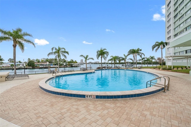 view of pool featuring a patio area and a water view