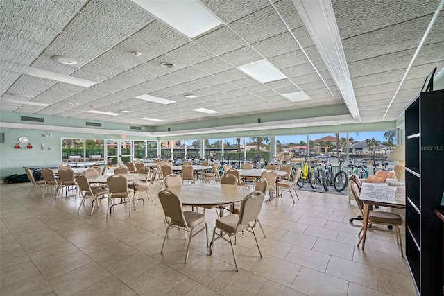 unfurnished dining area featuring a paneled ceiling, light tile patterned floors, and a wealth of natural light