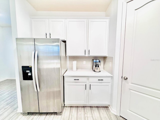 kitchen with white cabinets, decorative backsplash, light wood-type flooring, and stainless steel refrigerator with ice dispenser