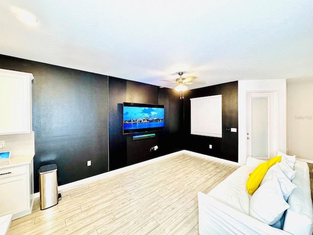 home theater room with ceiling fan and light hardwood / wood-style floors