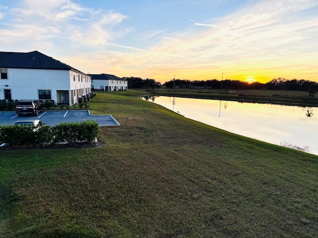 yard at dusk featuring a water view