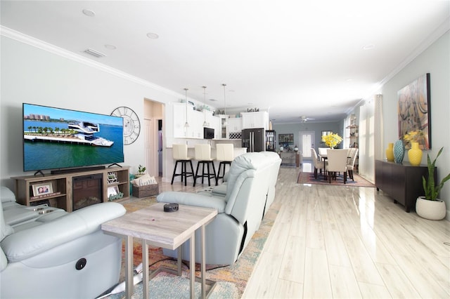 living room with ceiling fan, crown molding, and light hardwood / wood-style flooring