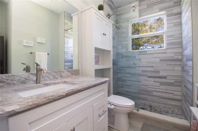 bathroom featuring tiled shower, vanity, and toilet