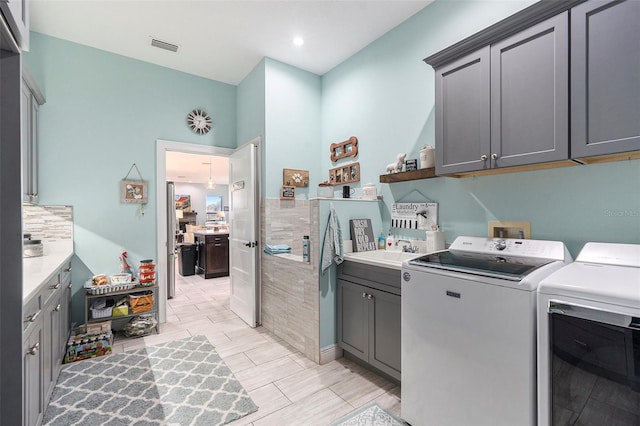 washroom with cabinets, sink, and washing machine and clothes dryer