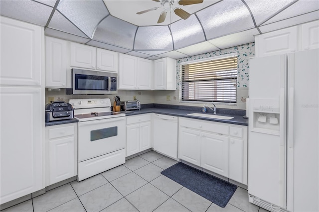 kitchen with white appliances, white cabinets, a paneled ceiling, sink, and light tile patterned floors