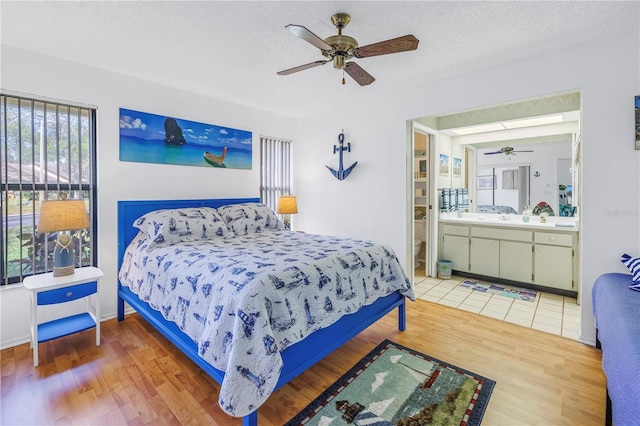 bedroom featuring ceiling fan, a textured ceiling, connected bathroom, and hardwood / wood-style floors