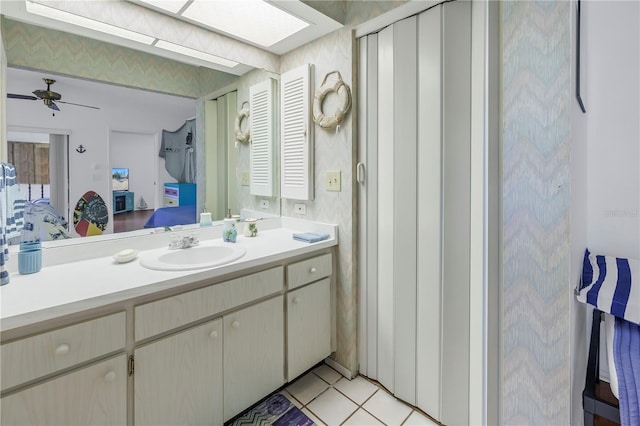 bathroom with ceiling fan, a skylight, tile patterned floors, and vanity