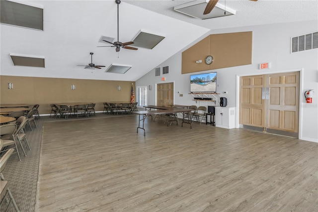 interior space featuring hardwood / wood-style flooring, a textured ceiling, high vaulted ceiling, and ceiling fan