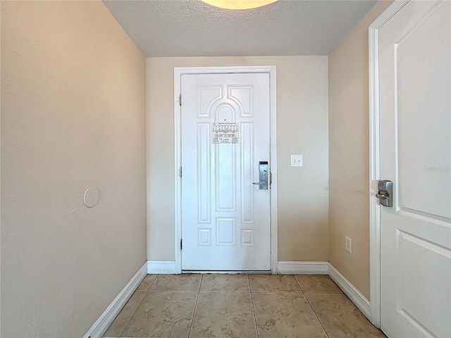 doorway to outside featuring light tile patterned floors and a textured ceiling