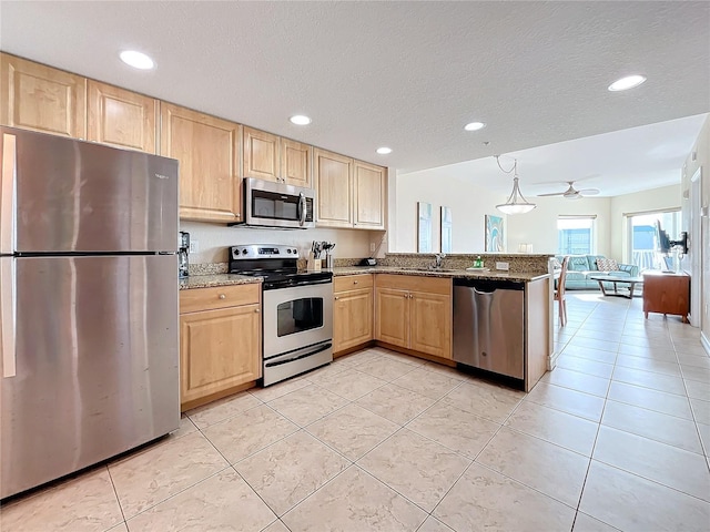 kitchen featuring light stone countertops, ceiling fan, kitchen peninsula, light tile patterned floors, and appliances with stainless steel finishes