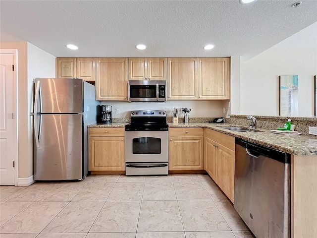 kitchen featuring sink, a textured ceiling, light brown cabinetry, appliances with stainless steel finishes, and light stone counters