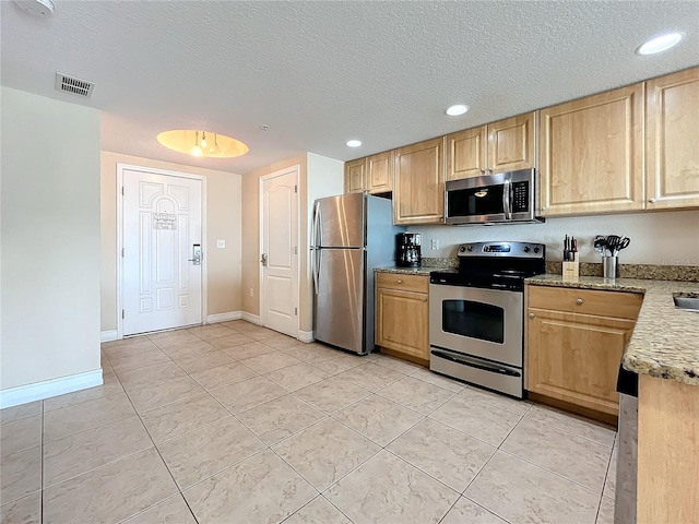 kitchen with light tile patterned floors, a textured ceiling, and stainless steel appliances