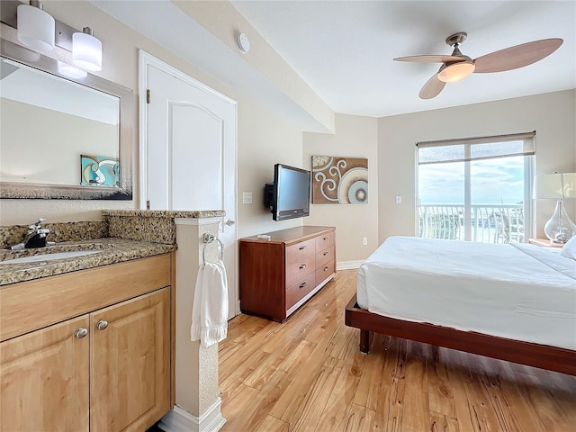 bedroom featuring access to outside, light hardwood / wood-style flooring, ceiling fan, and sink