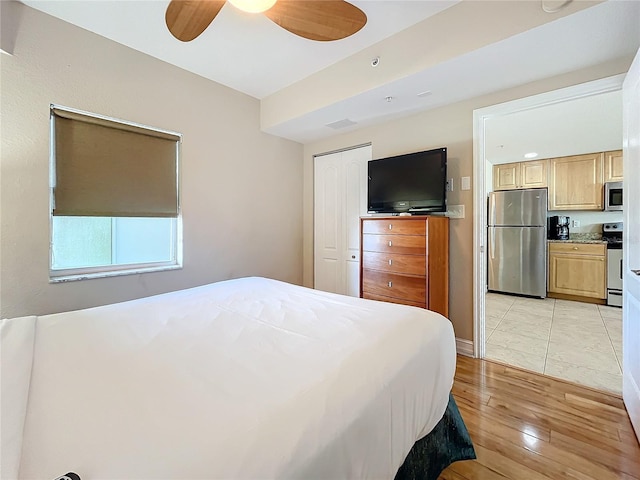 bedroom featuring a closet, stainless steel refrigerator, ceiling fan, and light hardwood / wood-style flooring