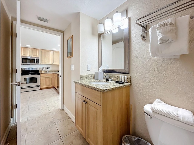 bathroom featuring tile patterned flooring, vanity, and toilet