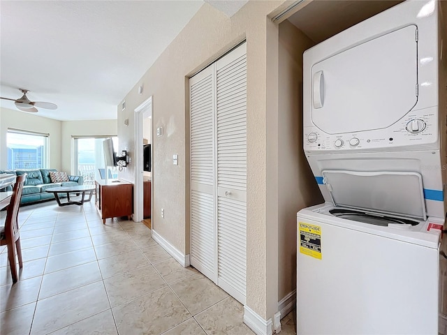 washroom featuring stacked washer / drying machine, ceiling fan, and light tile patterned floors