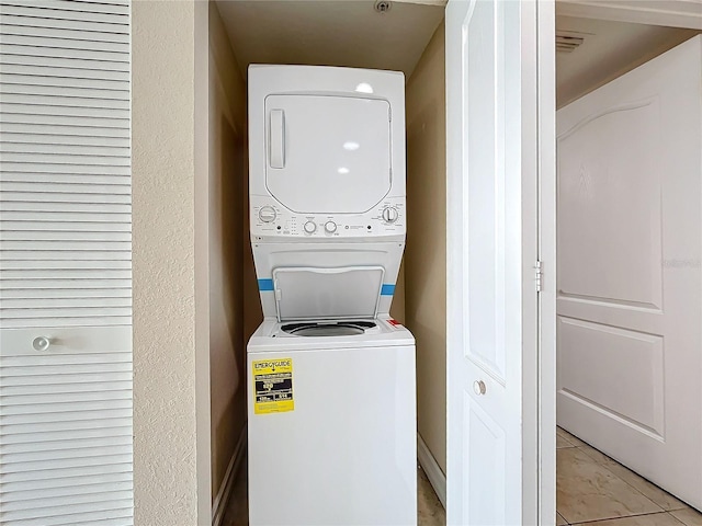 laundry area featuring stacked washing maching and dryer and light tile patterned flooring