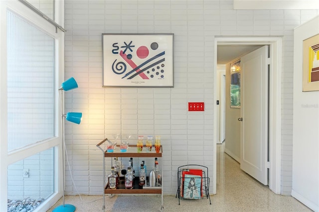 recreation room featuring speckled floor and tile walls