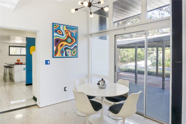 dining room with a chandelier, baseboards, speckled floor, and a high ceiling