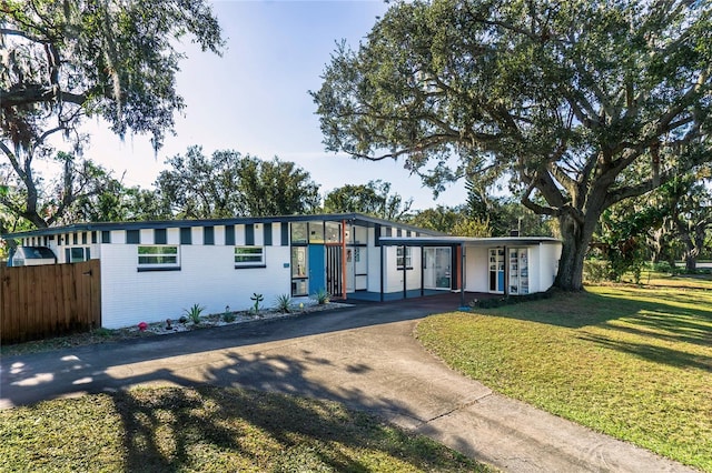 view of front of house with an attached carport, a front lawn, driveway, and fence