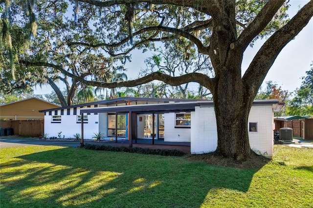 mid-century home featuring brick siding, central AC, a front lawn, and fence