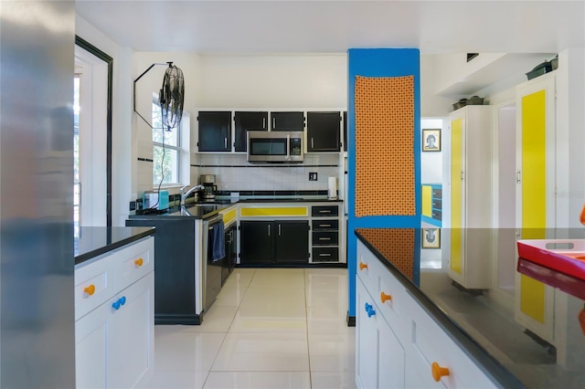 kitchen featuring stainless steel microwave, dark countertops, dark cabinets, and backsplash